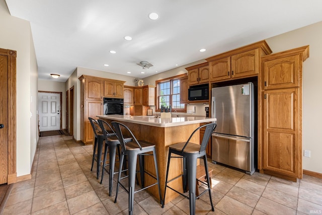 5595 N State Road 109, Columbia City, IN 46825 - kitchen featuring black appliances, a breakfast bar area, light countertops, a kitchen island, and brown cabinets