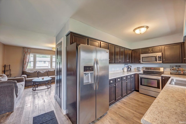 3121 S Yonkers St, Bloomington, IN 47403 - kitchen featuring stainless steel appliances, open floor plan, light wood-style floors, and dark brown cabinets