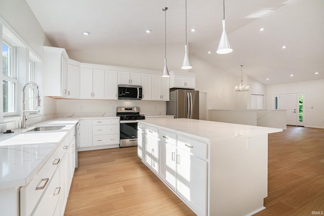54207 Starner Ave, Elkhart, IN 46514 - kitchen with appliances with stainless steel finishes, a kitchen island, light wood-style flooring, white cabinets, and light stone counters