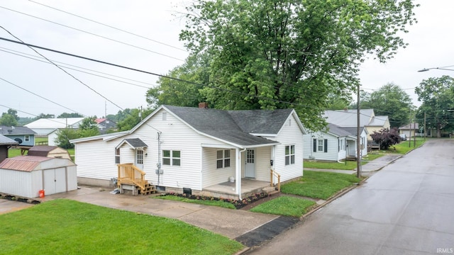 307 W Flora St, Washington, IN 47501 - bungalow-style house featuring a storage unit, roof with shingles, a front yard, and a chimney