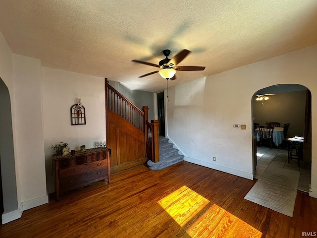 1114 W 4th St, Marion, IN 46952 - empty room featuring arched walkways, ceiling fan, wood finished floors, stairway, and a textured ceiling