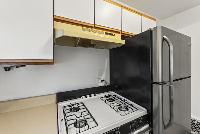 5309 S Hanna St, Fort Wayne, IN 46806 - kitchen featuring gas range gas stove, under cabinet range hood, white cabinetry, and freestanding refrigerator