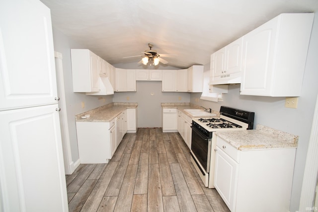 631 W 8th St, Bicknell, IN 47512 - kitchen with gas stove, a ceiling fan, under cabinet range hood, light wood-type flooring, and white cabinets