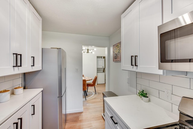 516 W Navarre St, South Bend, IN 46616 - kitchen featuring stainless steel microwave, range, light wood-style flooring, tasteful backsplash, and white cabinetry