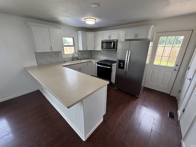 1821 E Johnson Ln, Vincennes, IN 47591 - kitchen featuring appliances with stainless steel finishes, light countertops, a peninsula, dark wood-style floors, and white cabinetry