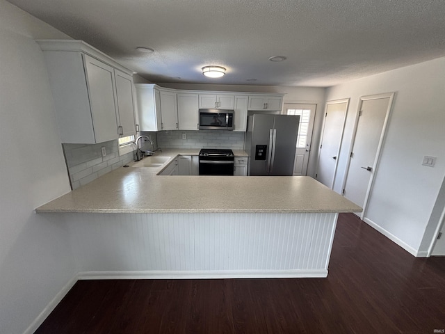 1821 E Johnson Ln, Vincennes, IN 47591 - kitchen featuring stainless steel appliances, light countertops, a peninsula, and dark wood-style flooring
