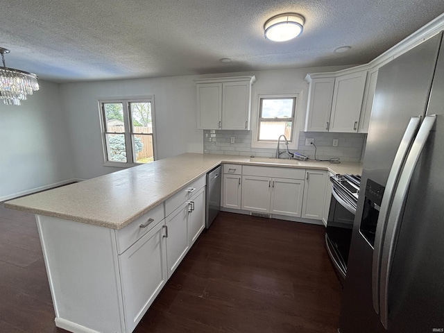 1821 E Johnson Ln, Vincennes, IN 47591 - kitchen featuring stainless steel appliances, a peninsula, a textured ceiling, plenty of natural light, and dark wood finished floors