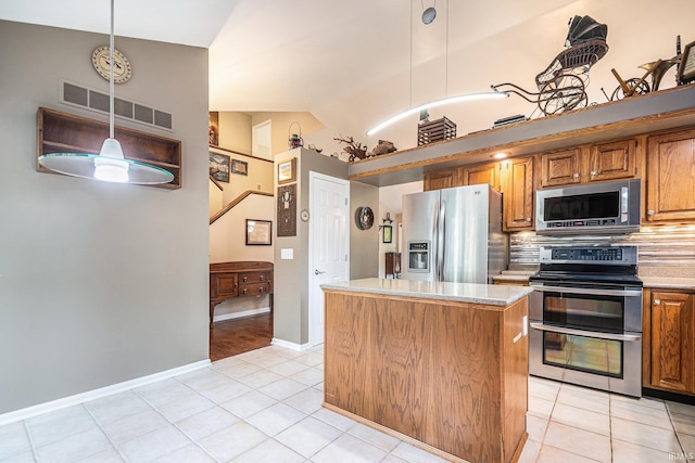 17991 Sable Ridge Dr, South Bend, IN 46635 - kitchen featuring appliances with stainless steel finishes, light tile patterned floors, a kitchen island, brown cabinets, and light countertops