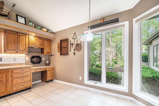 17991 Sable Ridge Dr, South Bend, IN 46635 - kitchen with light countertops, built in desk, backsplash, decorative light fixtures, and brown cabinetry