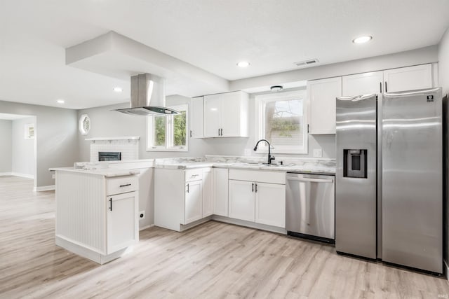3524 Contessa Dr, Fort Wayne, IN 46816 - kitchen with appliances with stainless steel finishes, a peninsula, light wood-style flooring, white cabinetry, and a brick fireplace
