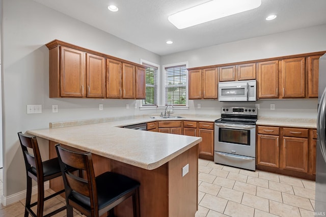 233 Sinclair Dr, West Lafayette, IN 47906 - kitchen with white microwave, stainless steel electric range oven, a peninsula, brown cabinetry, and light countertops