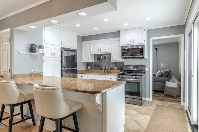 906 N Townline Rd, Lagrange, IN 46761 - kitchen featuring stainless steel appliances, crown molding, white cabinetry, a peninsula, and backsplash