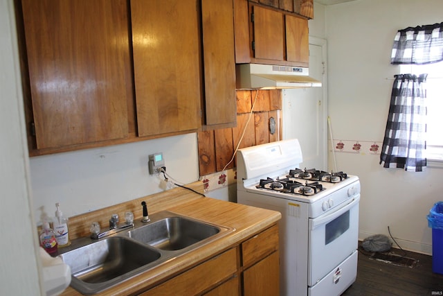 2012 S Vine St, Muncie, IN 47302 - kitchen featuring white gas stove, under cabinet range hood, light countertops, brown cabinetry, and dark wood-style floors