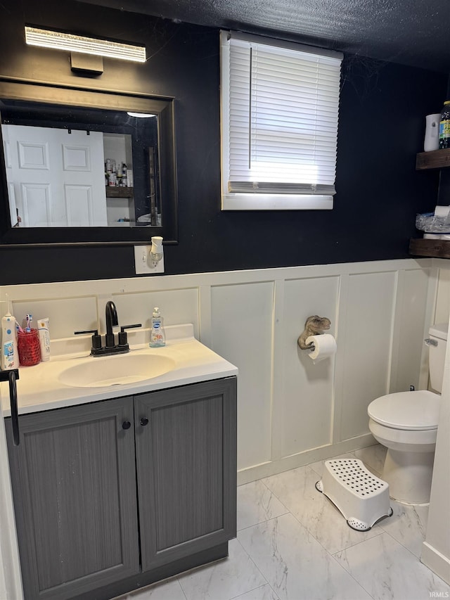 562 Railroad St, Wabash, IN 46992 - bathroom featuring marble look tile flooring, vanity, a decorative wall, and a wainscoted wall