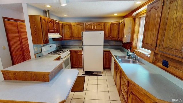 4115 N Aquarius Dr, Monticello, IN 47960 - kitchen featuring white appliances, under cabinet range hood, brown cabinets, a peninsula, and light countertops