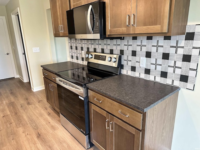1466 Monte Carlo Dr, Huntertown, IN 46748 - kitchen featuring stainless steel electric range, black microwave, backsplash, light wood finished floors, and dark countertops