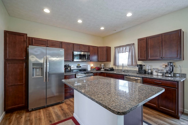 140 Wadsworth Ct, Lafayette, IN 47905 - kitchen featuring appliances with stainless steel finishes, dark wood-type flooring, a center island, a textured ceiling, and dark stone countertops