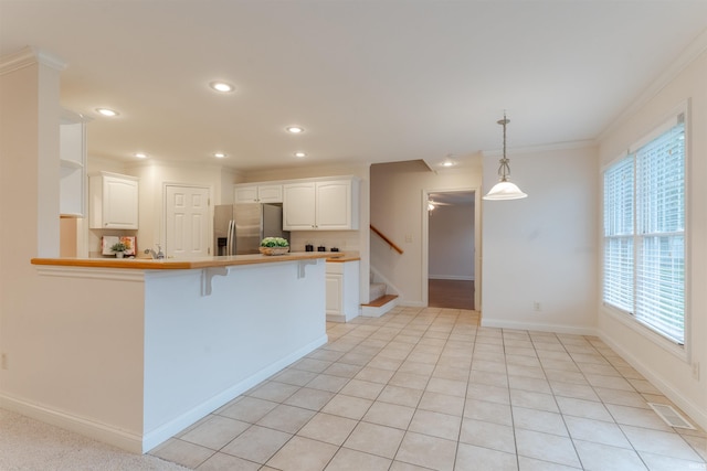 7561 Saint Jordan Cir, Newburgh, IN 47630 - kitchen with stainless steel fridge, crown molding, a peninsula, white cabinets, and a breakfast bar area