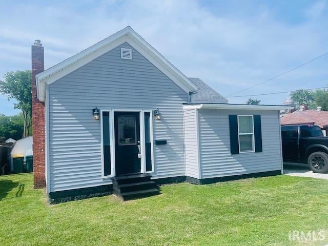 608 W Main St, Greentown, IN 46936 - rear view of house with entry steps, a lawn, and a chimney