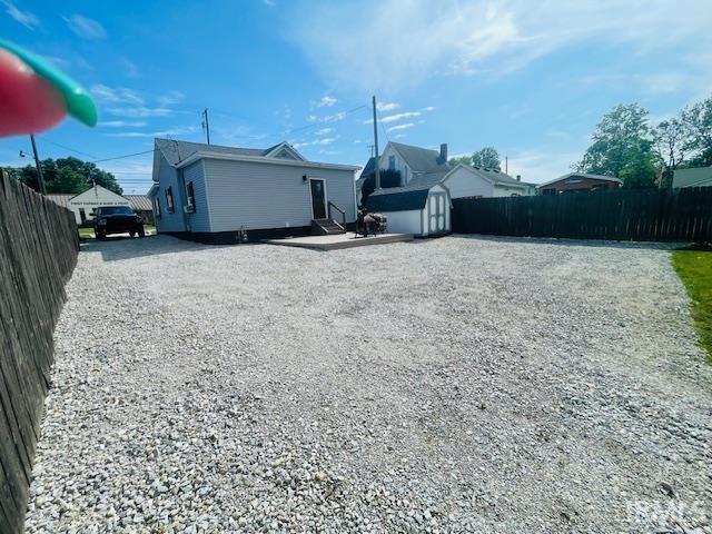 608 W Main St, Greentown, IN 46936 - back of property featuring a storage shed, gravel driveway, a fenced backyard, and entry steps