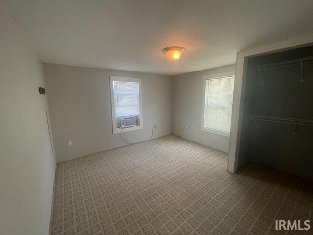 608 W Main St, Greentown, IN 46936 - unfurnished bedroom featuring multiple windows, cooling unit, and dark carpet