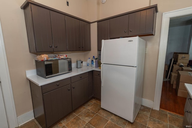 1121 S 23rd St, South Bend, IN 46615 - kitchen featuring freestanding refrigerator, dark stone finish flooring, light countertops, and dark brown cabinets