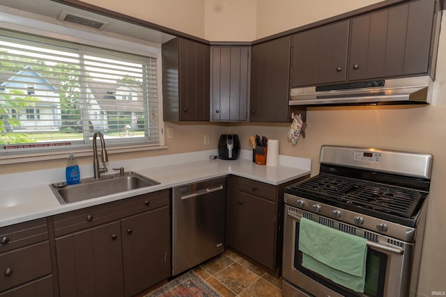 1121 S 23rd St, South Bend, IN 46615 - kitchen with stainless steel appliances, under cabinet range hood, dark brown cabinets, light countertops, and dark stone finish floors