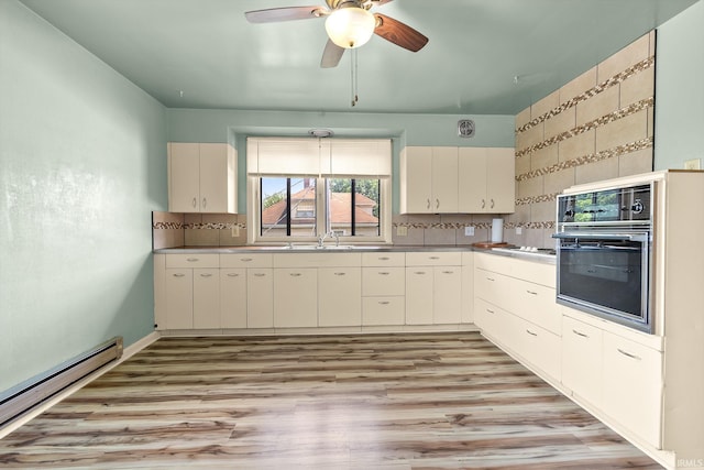 1208 Delta Blvd, Fort Wayne, IN 46805 - kitchen with oven, a baseboard radiator, a ceiling fan, light wood-style flooring, and decorative backsplash