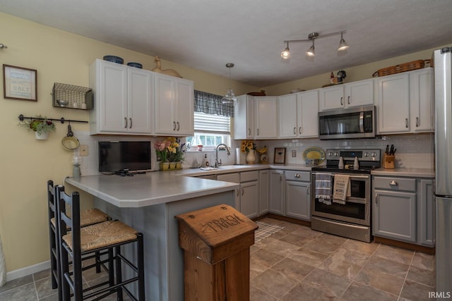 4600 N Shadow Wood Dr, Bloomington, IN 47404 - kitchen with stainless steel appliances, gray cabinets, decorative backsplash, a breakfast bar, and a peninsula