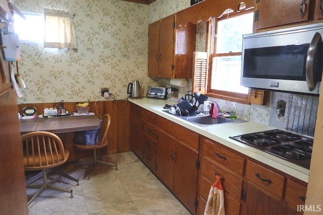 1120 E Fourth St, Mount Vernon, IN 47620 - kitchen with stainless steel microwave, gas cooktop, light countertops, wallpapered walls, and a wainscoted wall
