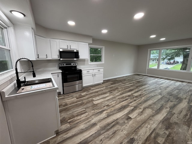 205 Corwin Ln, Fort Wayne, IN 46816 - kitchen with stainless steel appliances, white cabinets, dark wood finished floors, light countertops, and plenty of natural light