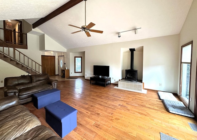 3108 E Charles Ct, Bloomington, IN 47401 - living room with light wood-type flooring, a wood stove, stairway, beamed ceiling, and a ceiling fan