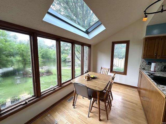 3108 E Charles Ct, Bloomington, IN 47401 - dining room featuring a skylight, vaulted ceiling, and light wood-style flooring