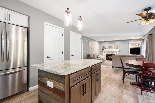 14341 Teal Ct, Granger, IN 46530 - kitchen featuring freestanding refrigerator, light wood-style floors, a stone fireplace, ceiling fan, and light stone counters