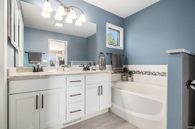 14341 Teal Ct, Granger, IN 46530 - full bathroom with double vanity, a garden tub, wood finished floors, and a chandelier