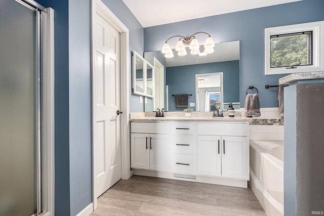 14341 Teal Ct, Granger, IN 46530 - full bath featuring wood finished floors, double vanity, a garden tub, a shower stall, and a chandelier