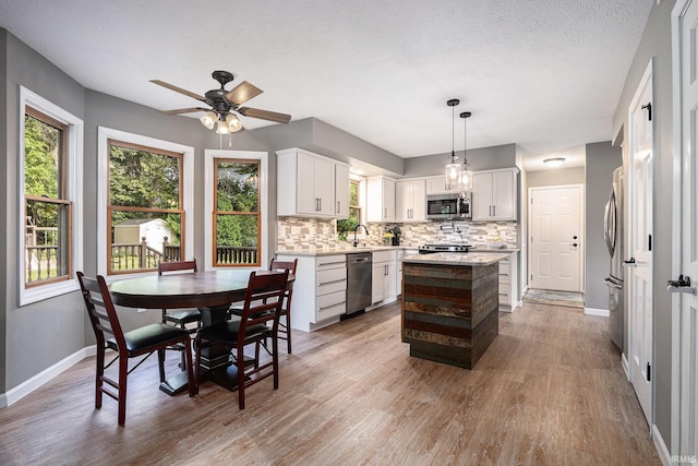14341 Teal Ct, Granger, IN 46530 - kitchen featuring stainless steel appliances, tasteful backsplash, light countertops, wood finished floors, and a textured ceiling