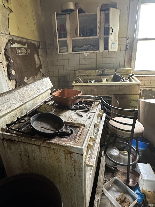 1127 S Jefferson St, Muncie, IN 47302 - kitchen with white range with gas cooktop, tile walls, and backsplash