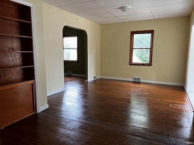 1026 E Wayne St, South Bend, IN 46617 - empty room with arched walkways, plenty of natural light, dark wood-style floors, and a drop ceiling