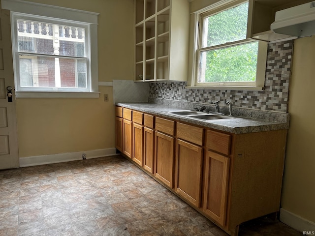 1026 E Wayne St, South Bend, IN 46617 - kitchen featuring plenty of natural light, backsplash, brown cabinetry, and stone finish floors