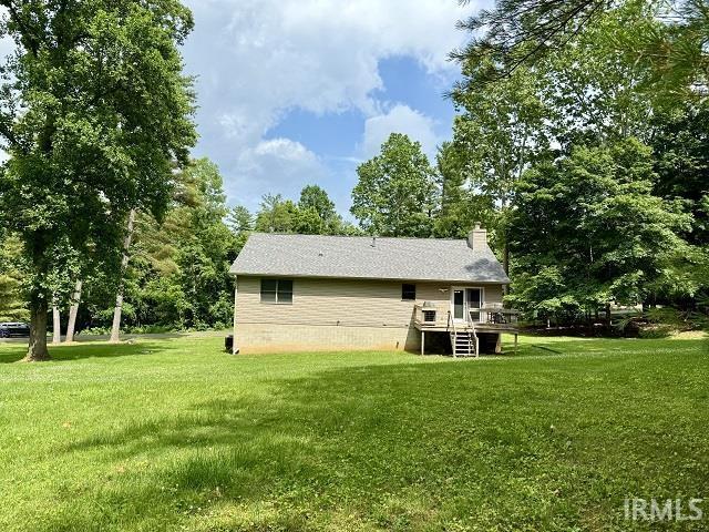 5918 S Foxwood Ln, Bloomington, IN 47401 - rear view of house featuring a deck, a yard, a chimney, and view of scattered trees