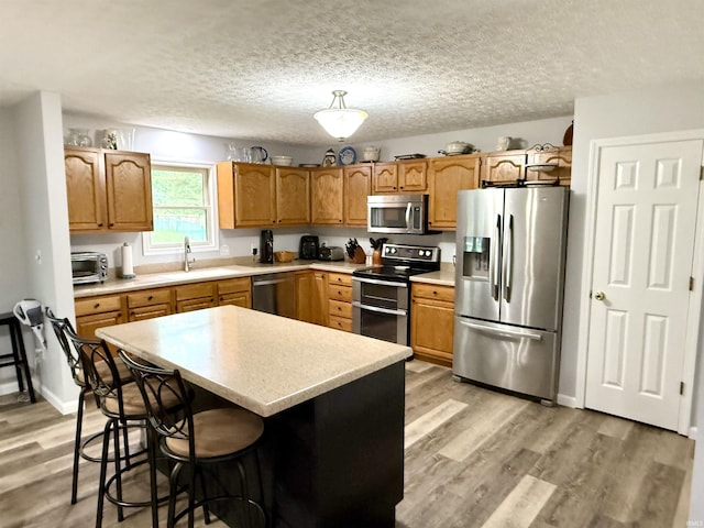 5918 S Foxwood Ln, Bloomington, IN 47401 - kitchen featuring stainless steel appliances, light wood-type flooring, light countertops, a kitchen bar, and a kitchen island