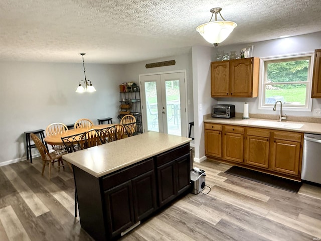 5918 S Foxwood Ln, Bloomington, IN 47401 - kitchen with stainless steel dishwasher, light countertops, a textured ceiling, hanging light fixtures, and light wood finished floors