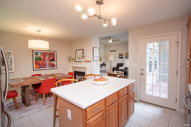 44 Fairfieldview Ct, Lafayette, IN 47905 - kitchen featuring light tile patterned floors, a fireplace, a ceiling fan, a center island, and a breakfast bar area
