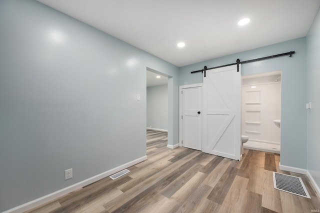 32 W Main St, Redkey, IN 47373 - unfurnished bedroom with a barn door, wood finished floors, recessed lighting, ensuite bathroom, and a closet