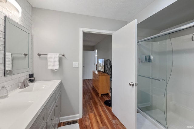 2770 N Baers Ct, Monticello, IN 47960 - bathroom with double vanity, wood finished floors, a shower stall, and tasteful backsplash