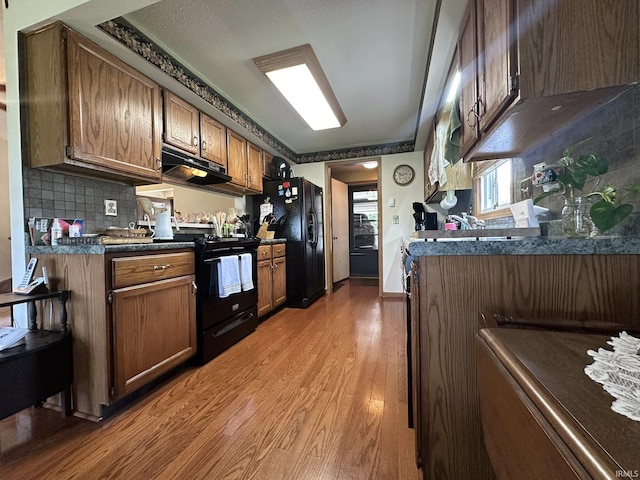 15908 Walnut St, Huntertown, IN 46748 - kitchen with black appliances, under cabinet range hood, light wood finished floors, backsplash, and dark countertops
