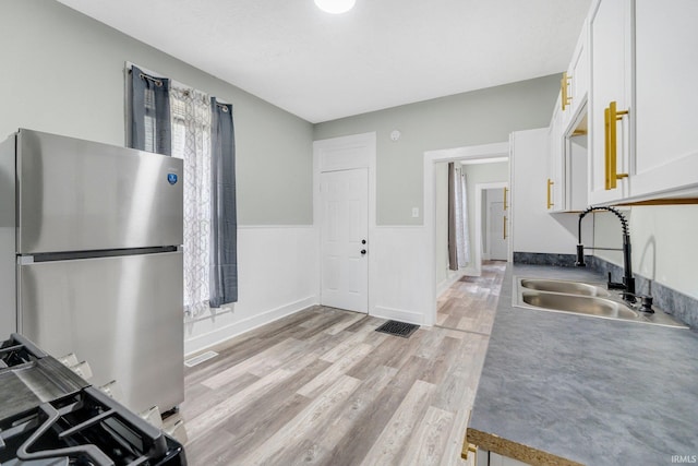 1409 Oakland St, Fort Wayne, IN 46808 - kitchen with freestanding refrigerator, white cabinetry, and light wood-type flooring