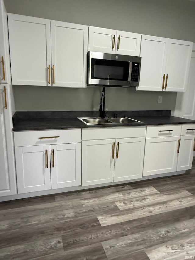 1409 Oakland St, Fort Wayne, IN 46808 - kitchen featuring stainless steel microwave, white cabinetry, dark countertops, and dark wood-style flooring