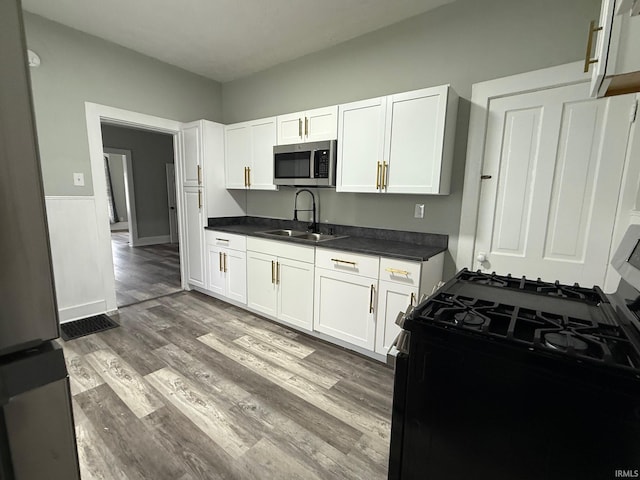 1409 Oakland St, Fort Wayne, IN 46808 - kitchen featuring appliances with stainless steel finishes, dark countertops, white cabinets, and wood finished floors